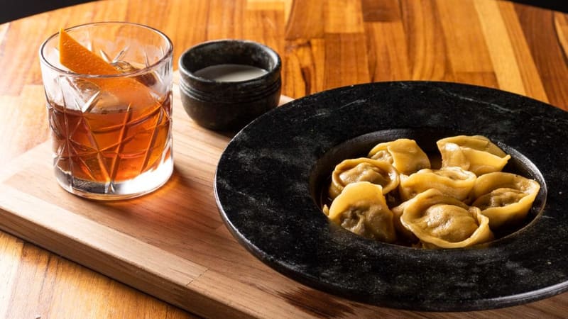 Pelmeni, um dos pratos oferecidos no Bräuhaus Restobier. Tem Massa fresca recheada de carne, caldo caseiro de costela e sour cream, uma receita originalmente russa. Ele está acompanhado de um drink de cerveja, o Bear Hunting | Foto: Assessoria